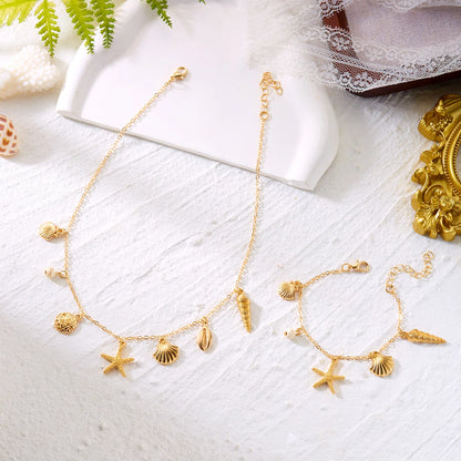 Flat lay of the Cove gold charm chain necklace and bracelet with seashell styling
