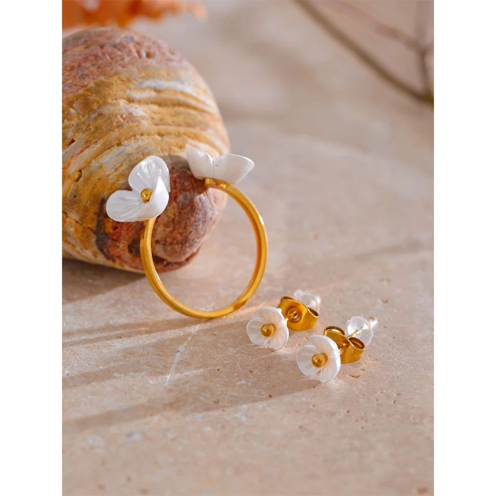 Rhea Blossom gold ring with white resin flowers beside stud earrings