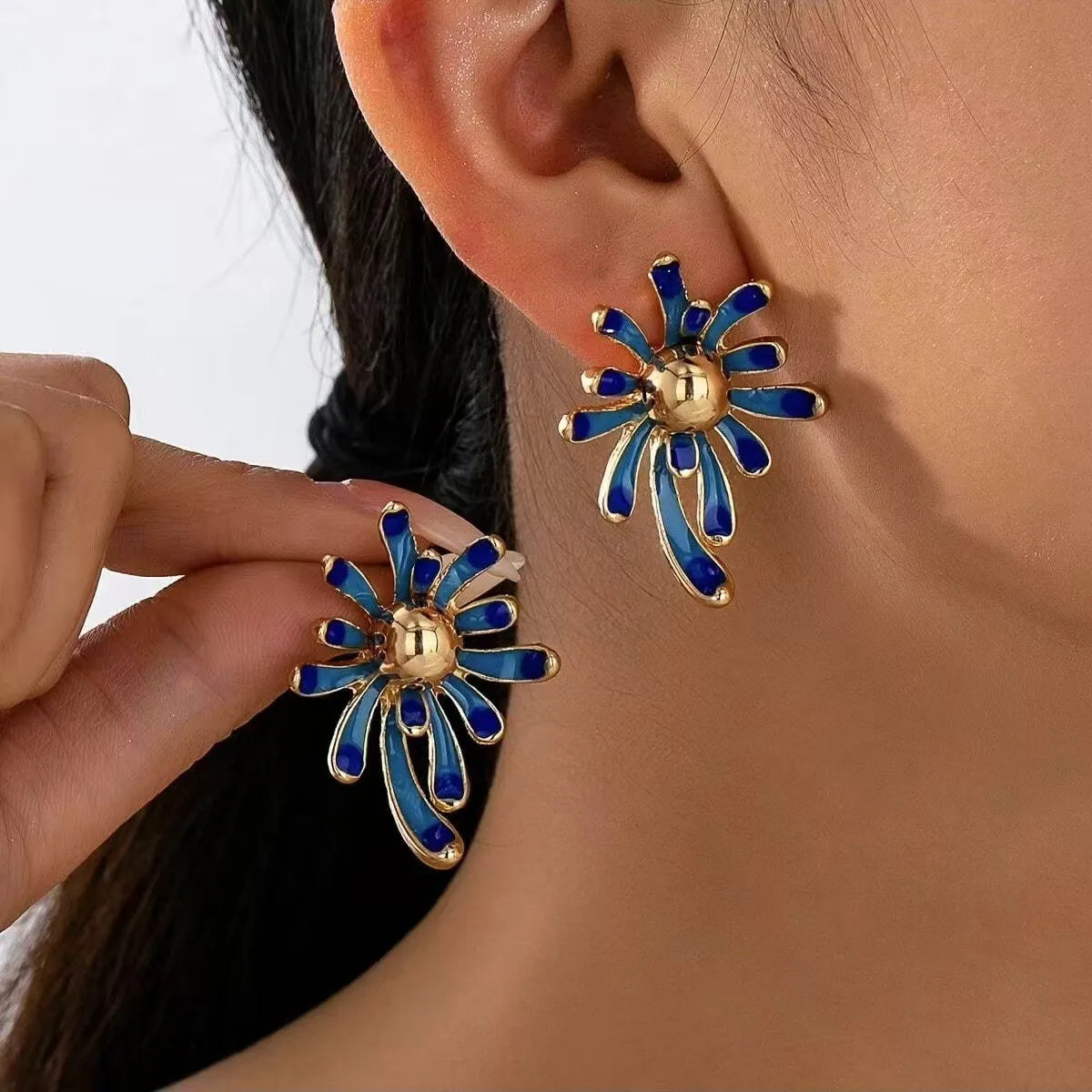 Solene blue enamel starburst earrings on model