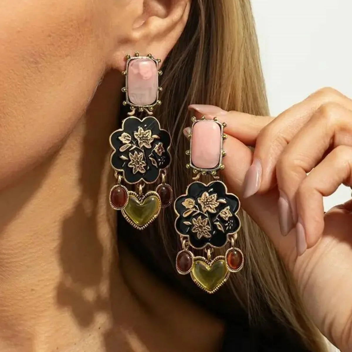 Model wearing Bellamy vintage floral drop earring, holding the matching second earring