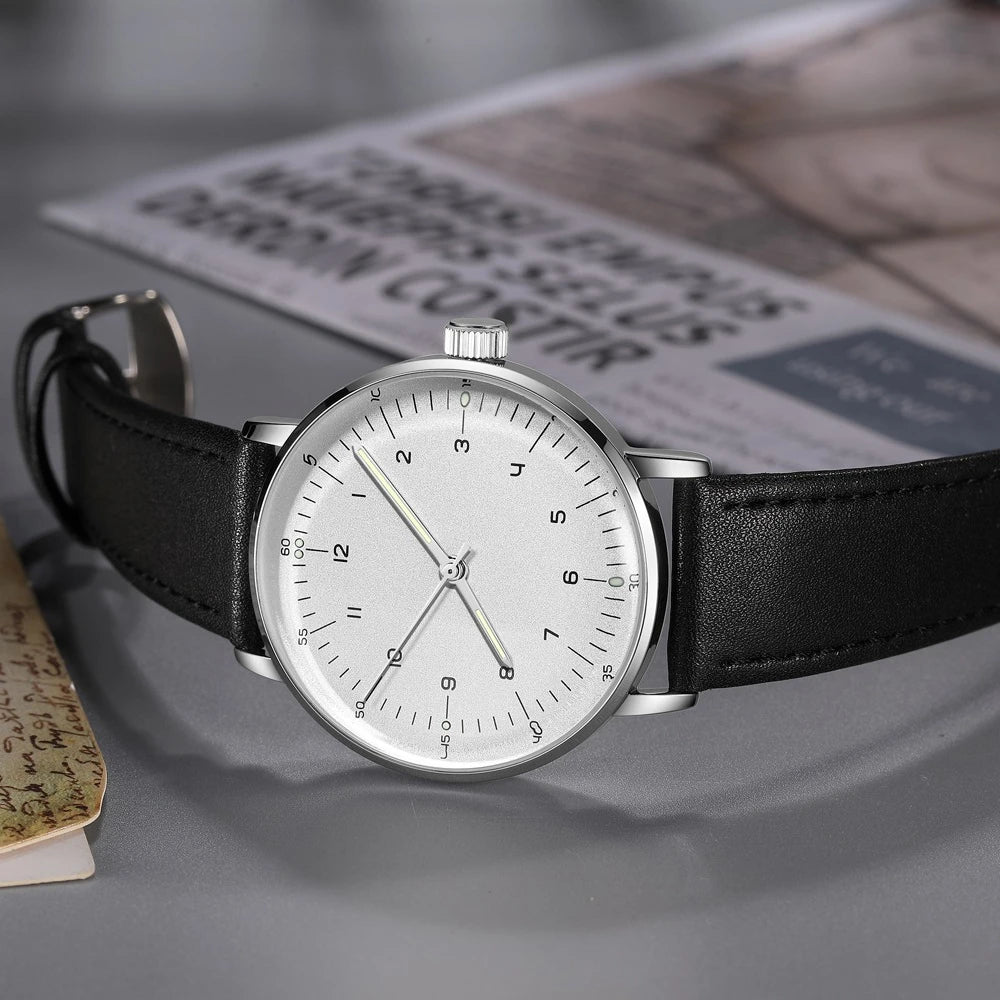 Minimalist mechanical watch resting on a grey surface