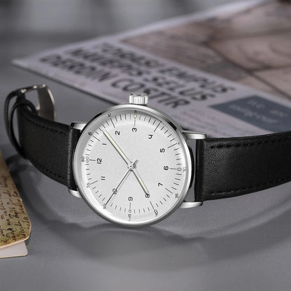 Minimalist mechanical watch resting on a grey surface