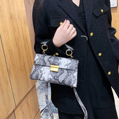 Serra snake-print top-handle bag in black worn crossbody