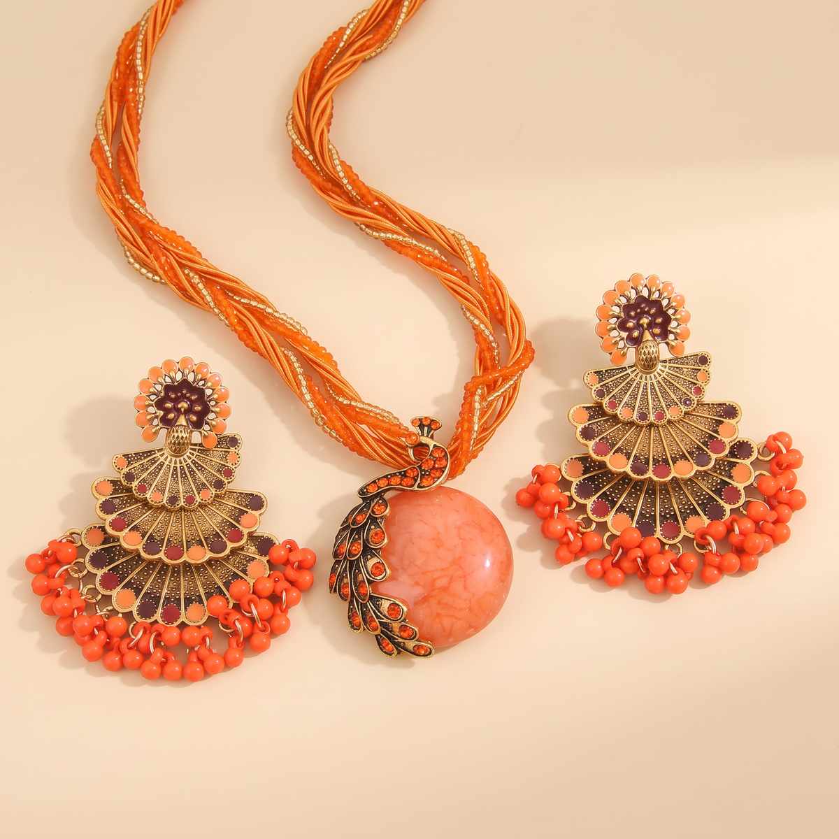 Alba Peacock Jewelry Set in Coral Orange, beaded strands and peacock pendant studio flat lay