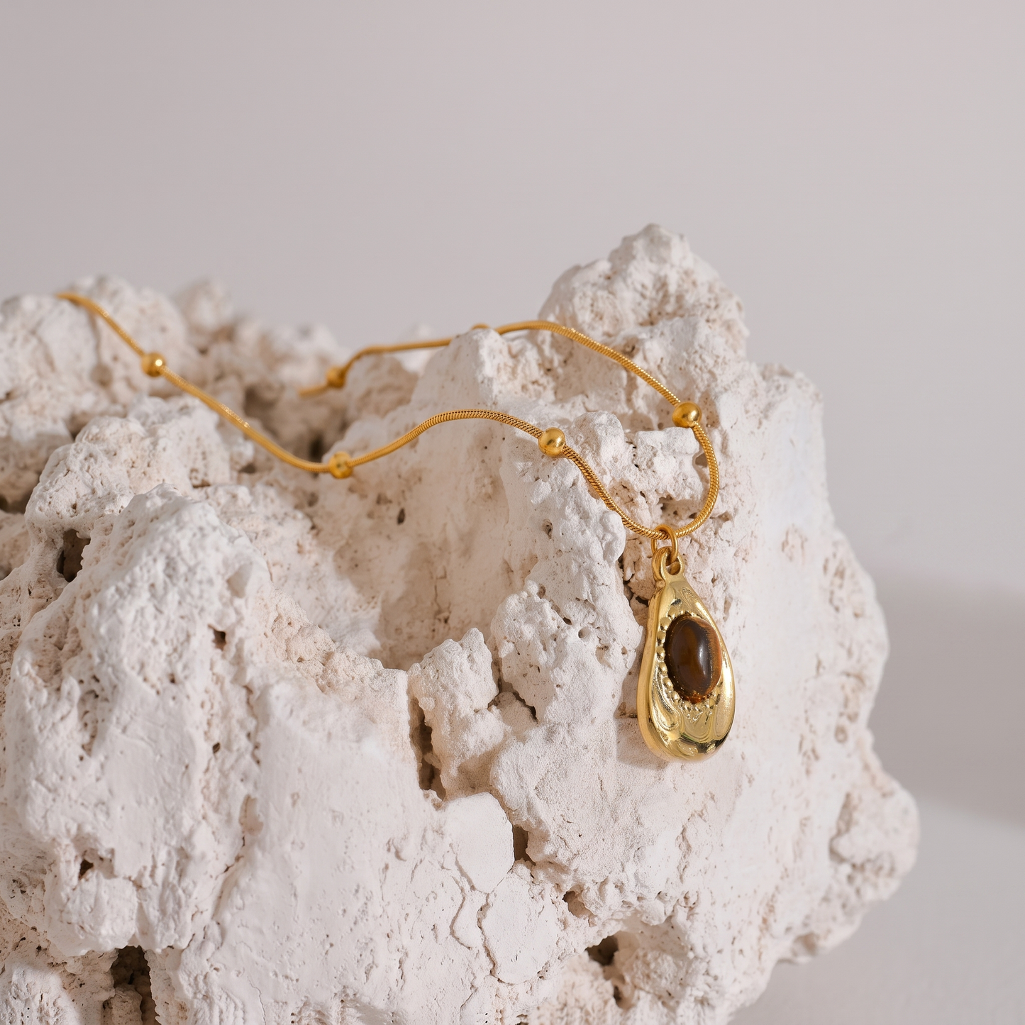 Asha Tiger-Eye Pendant styled on natural stone with tiger's eye