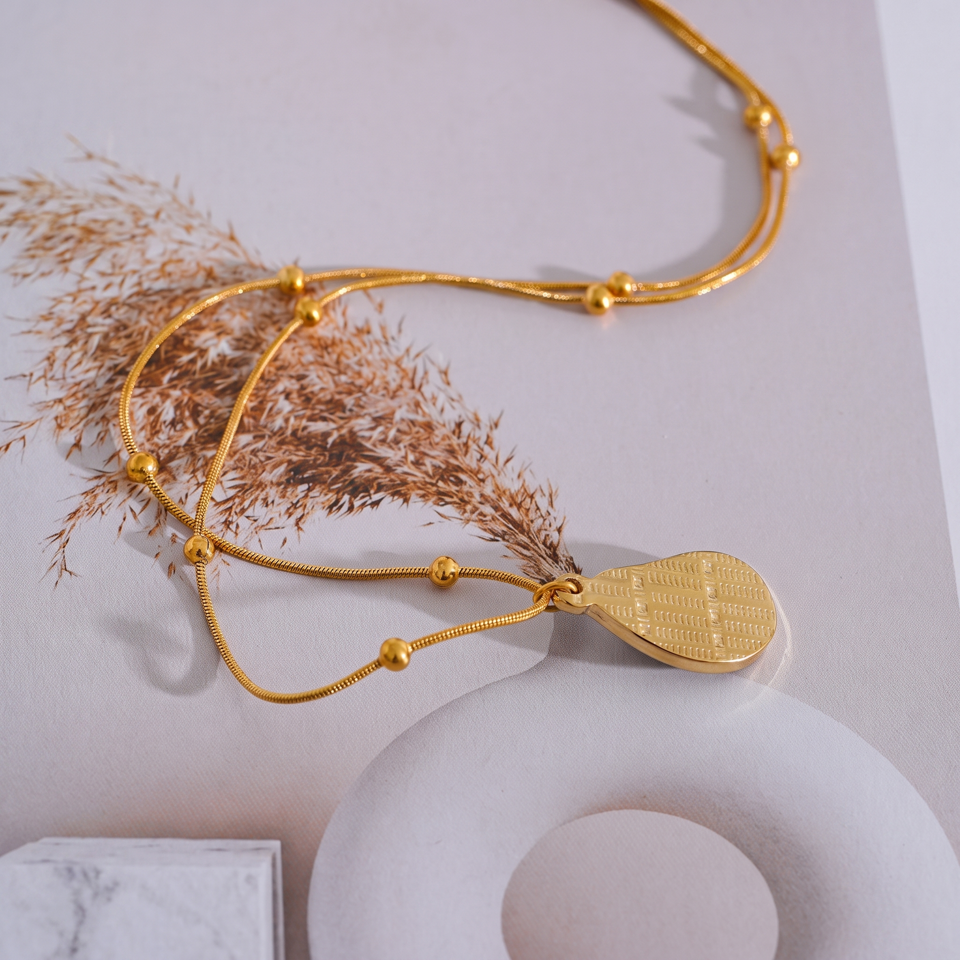 Asha Tiger-Eye Pendant flat lay with dried grass accent
