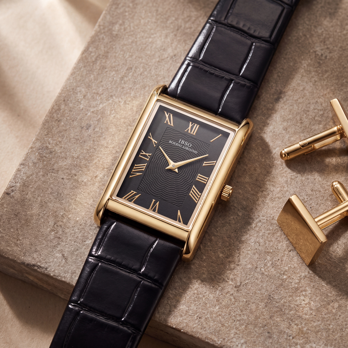 Carlyle rectangular dress watch in gold-tone, angled on a warm stone slab beside a pair of gold cufflinks