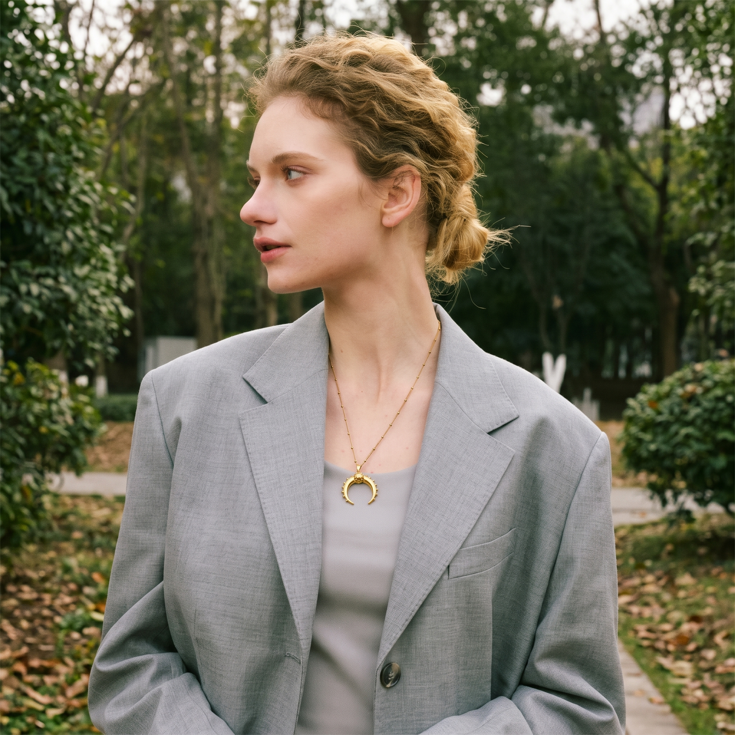 Celeste Moon Pendant Necklace in gold, laid out near a ceramic vase