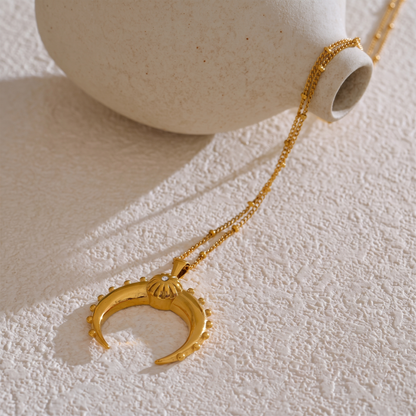 Celeste Moon Pendant Necklace in gold, resting on a stone surface