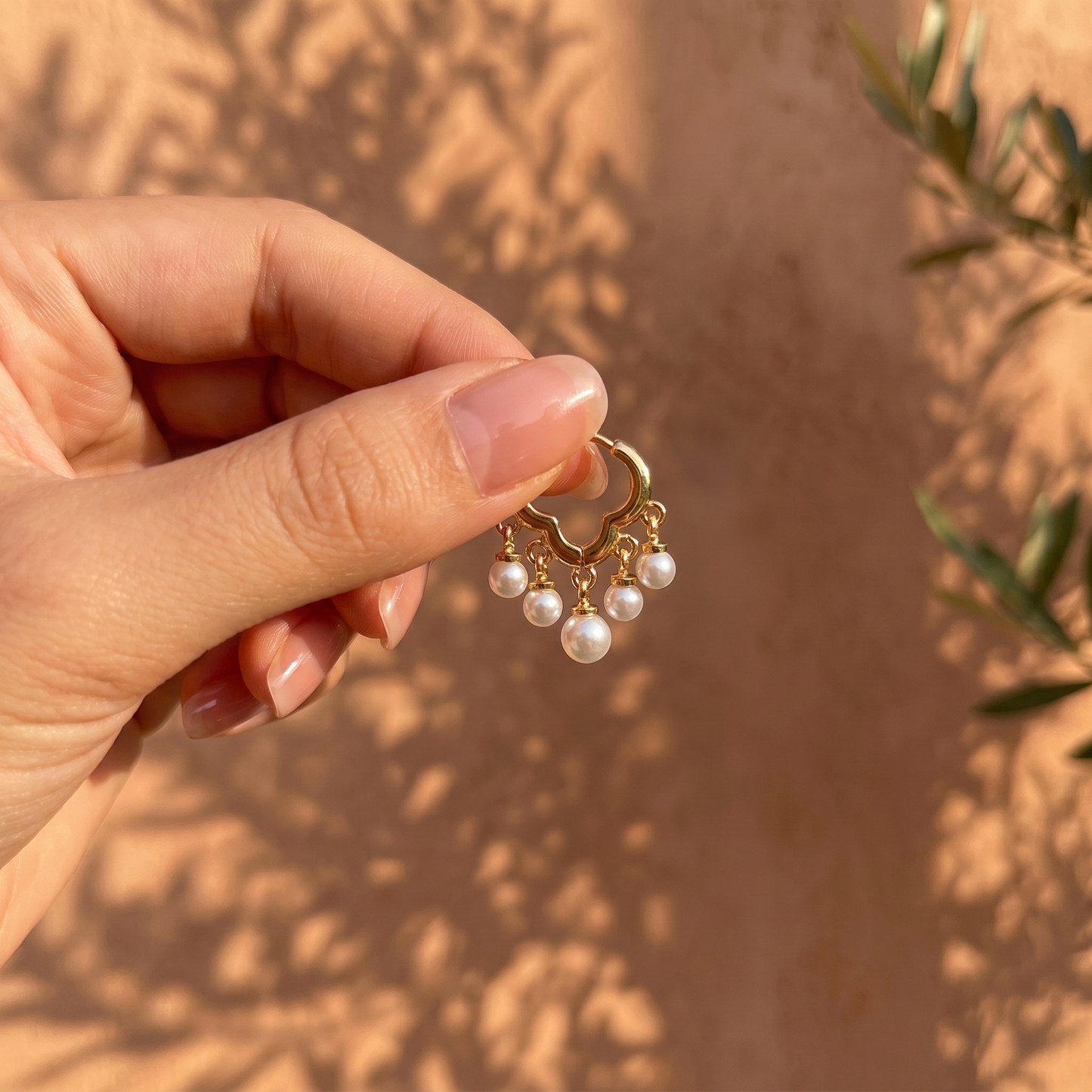 Daisy gold pearl huggie earrings held