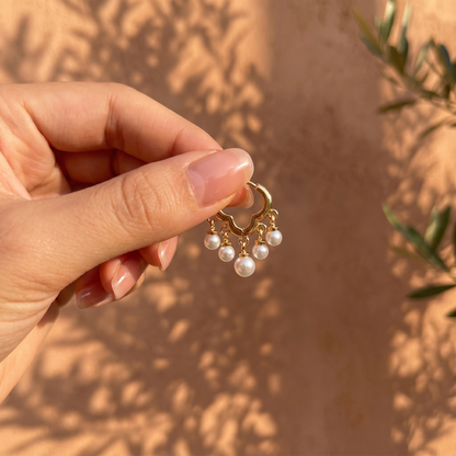 Daisy gold pearl huggie earrings held