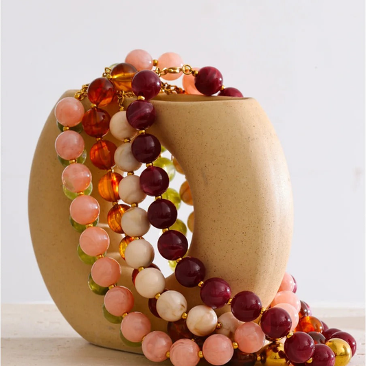 Malibu resin bead necklaces in all five colorways draped over a ceramic vase