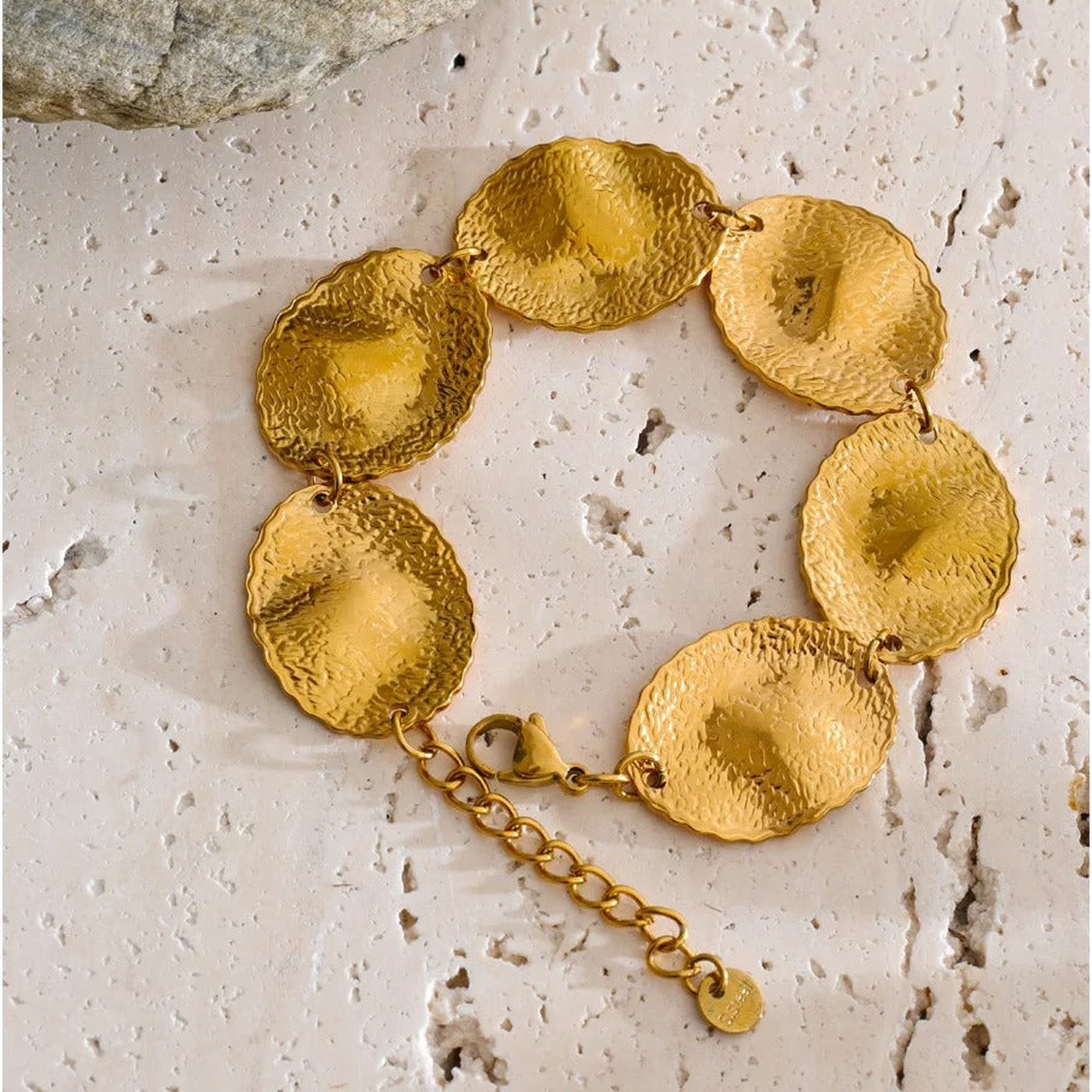 Blakely hammered gold-tone disc bracelet on a travertine surface