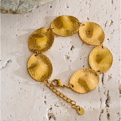 Blakely hammered gold-tone disc bracelet on a travertine surface