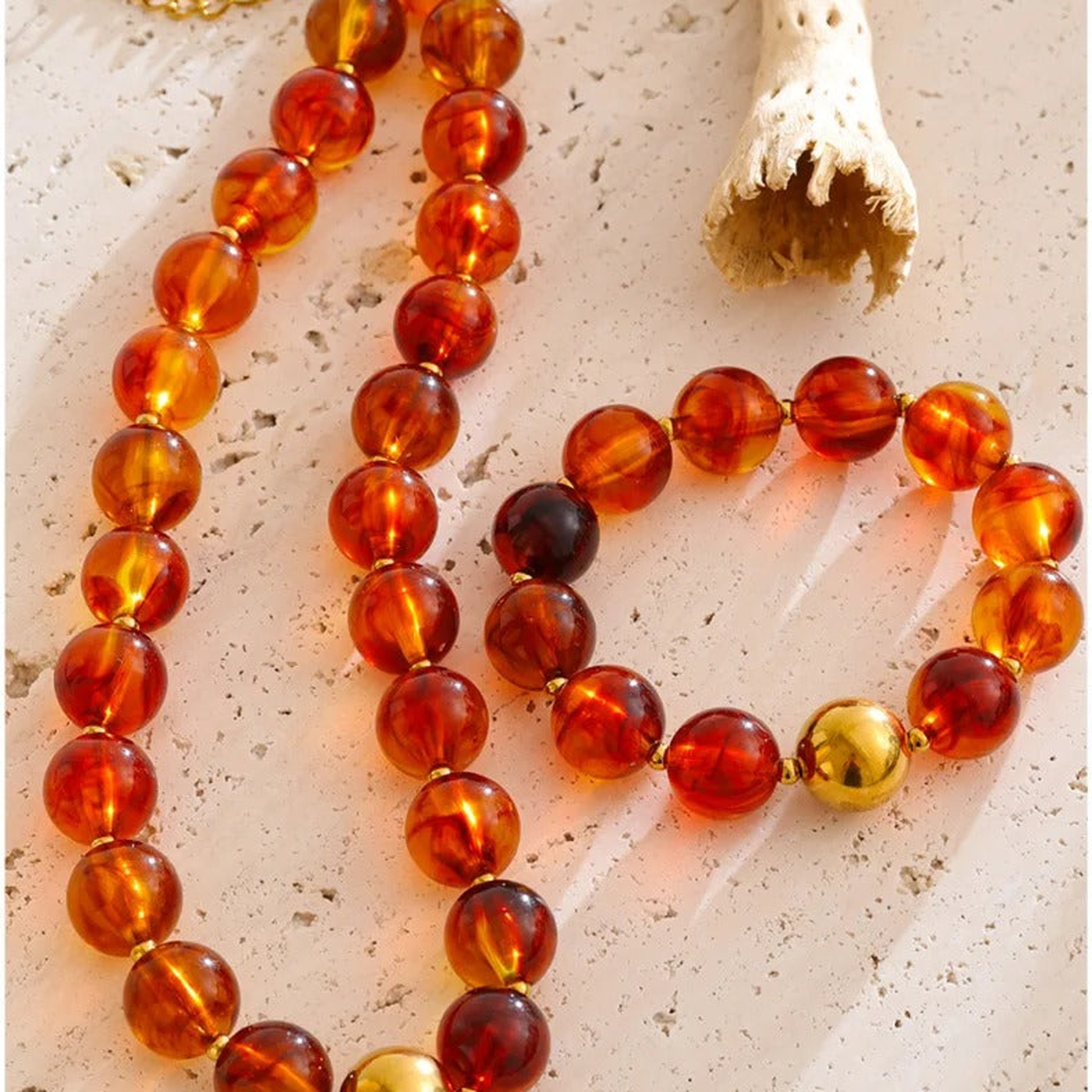 Malibu amber resin bead necklace and bracelet set on a stone surface