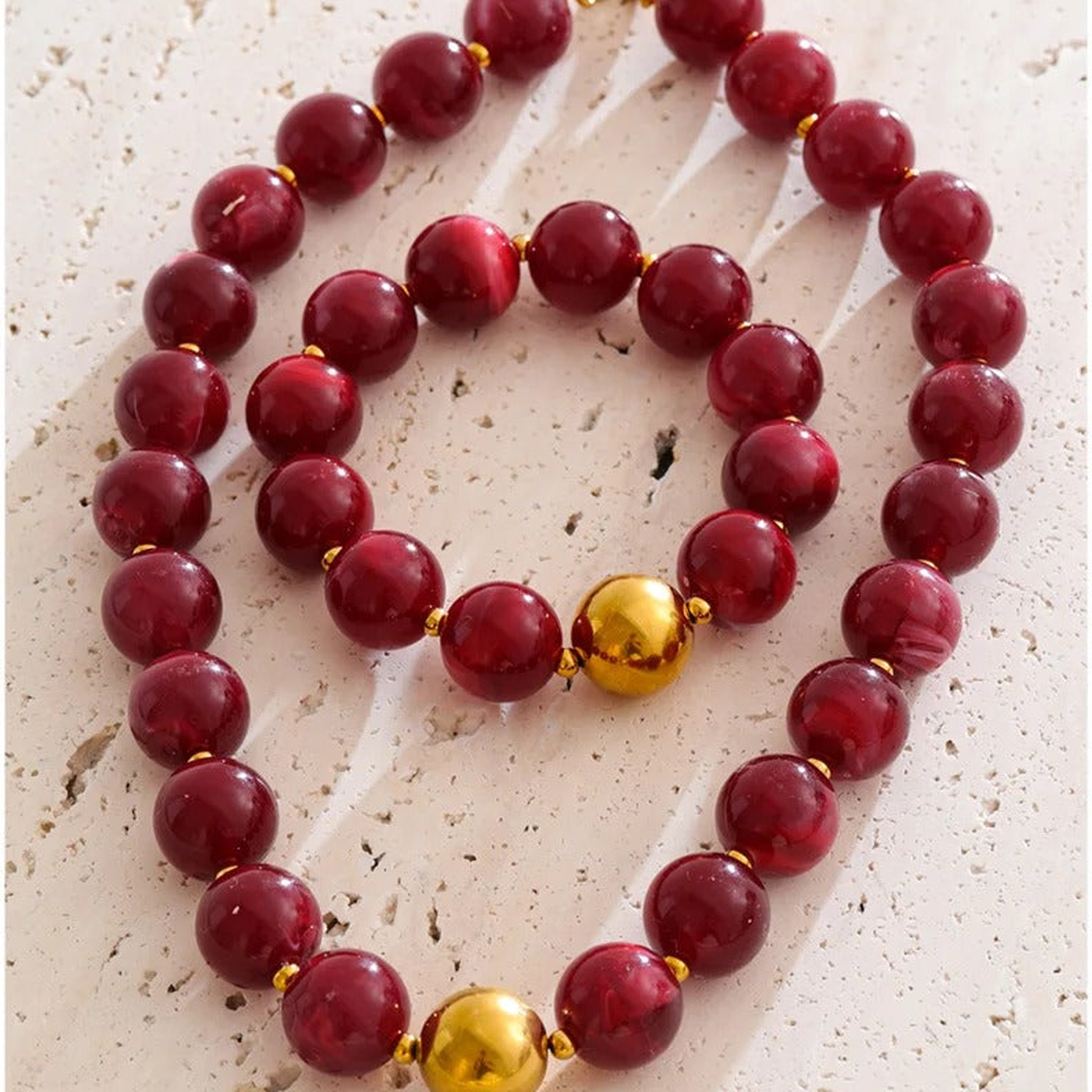 Malibu crimson resin bead necklace and bracelet set on a stone surface