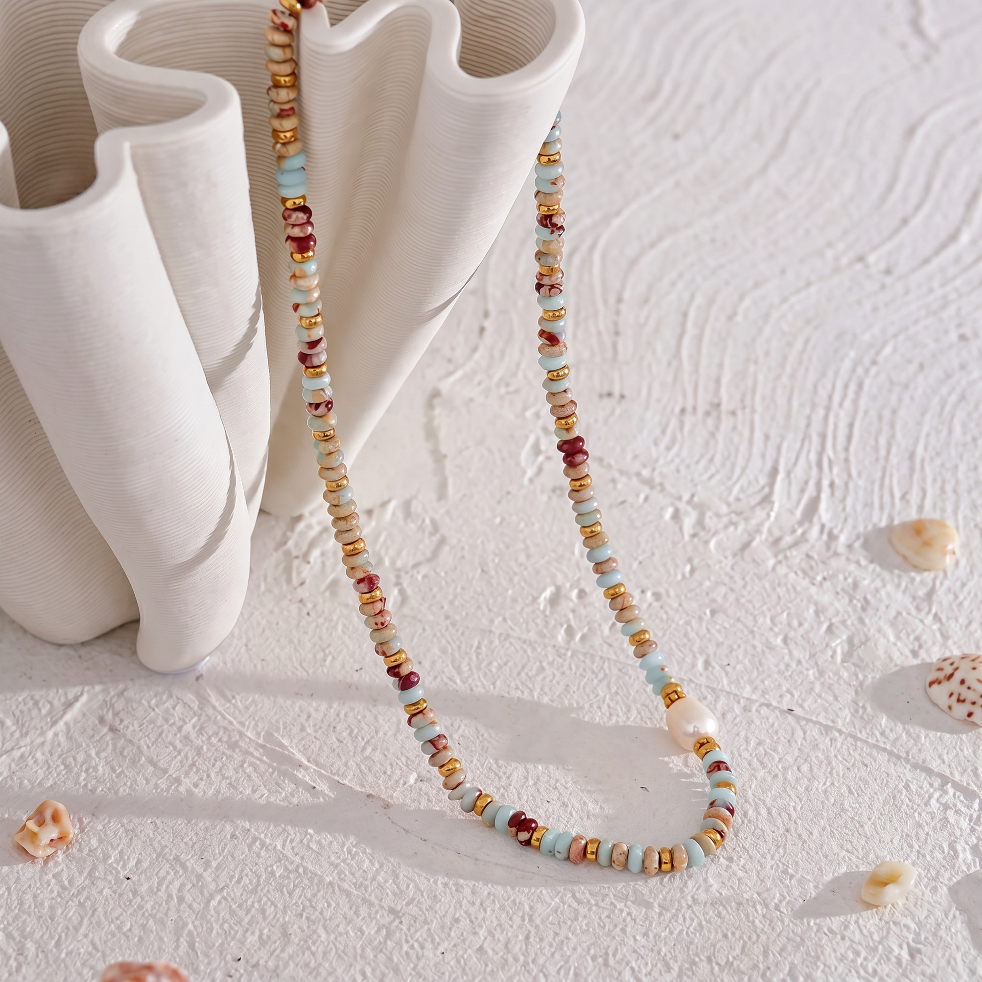 Livia Aqua Terra beaded jasper necklace displayed with a white wavy ceramic vase
