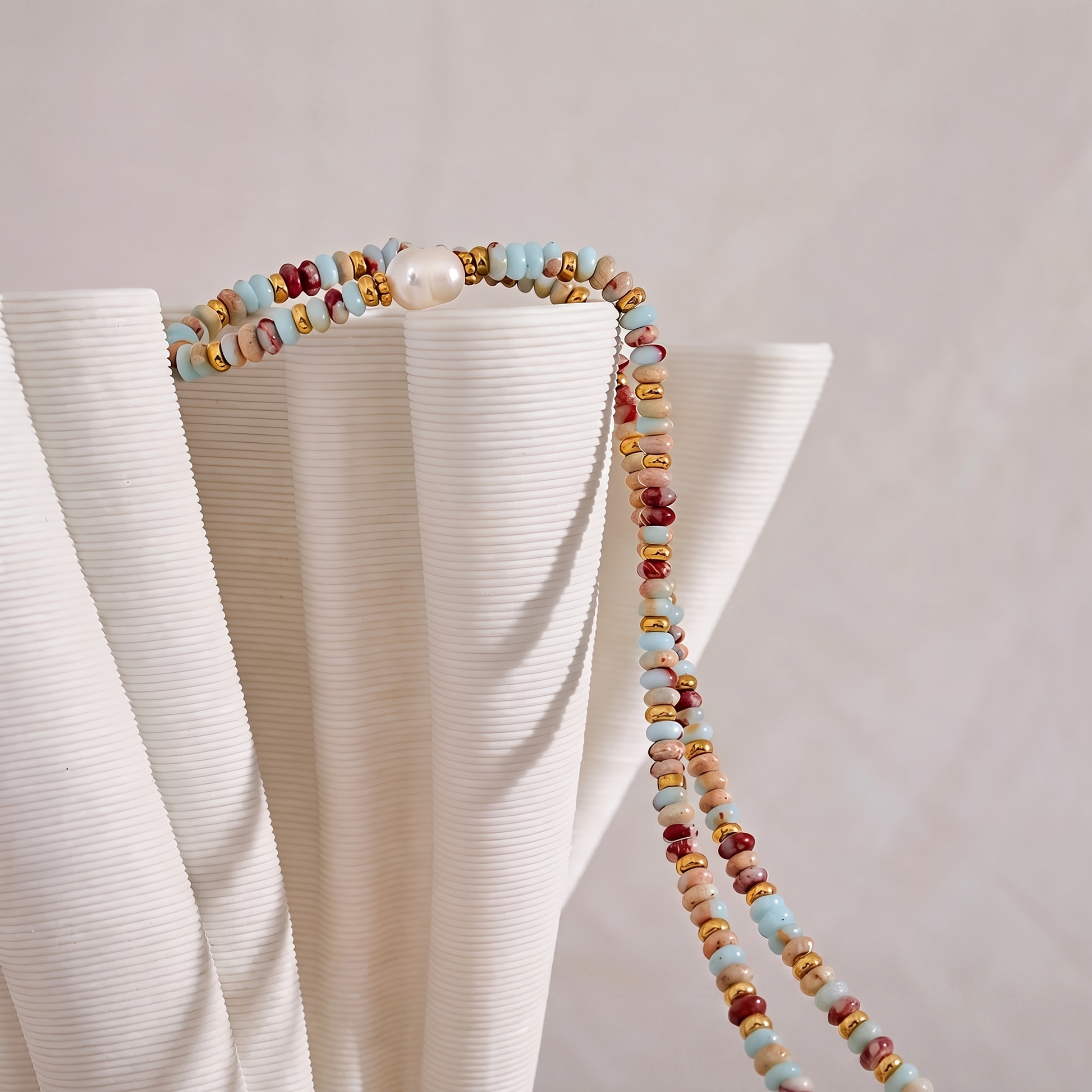 Livia Aqua Terra beaded jasper necklace draped over ribbed white ceramic