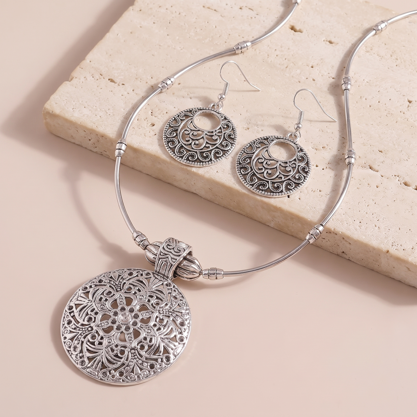 Lucca medallion necklace and earrings styled on a stone ledge