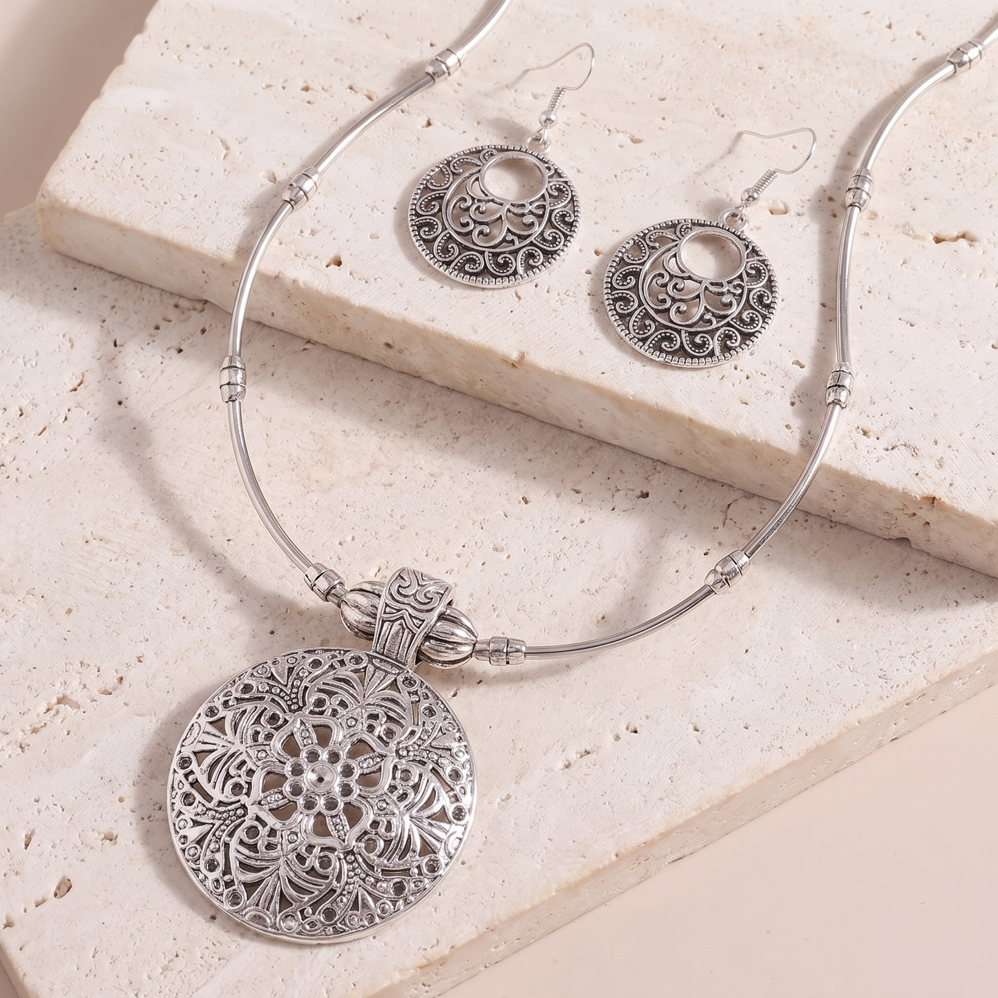 Lucca medallion pendant and earrings on a stone ledge