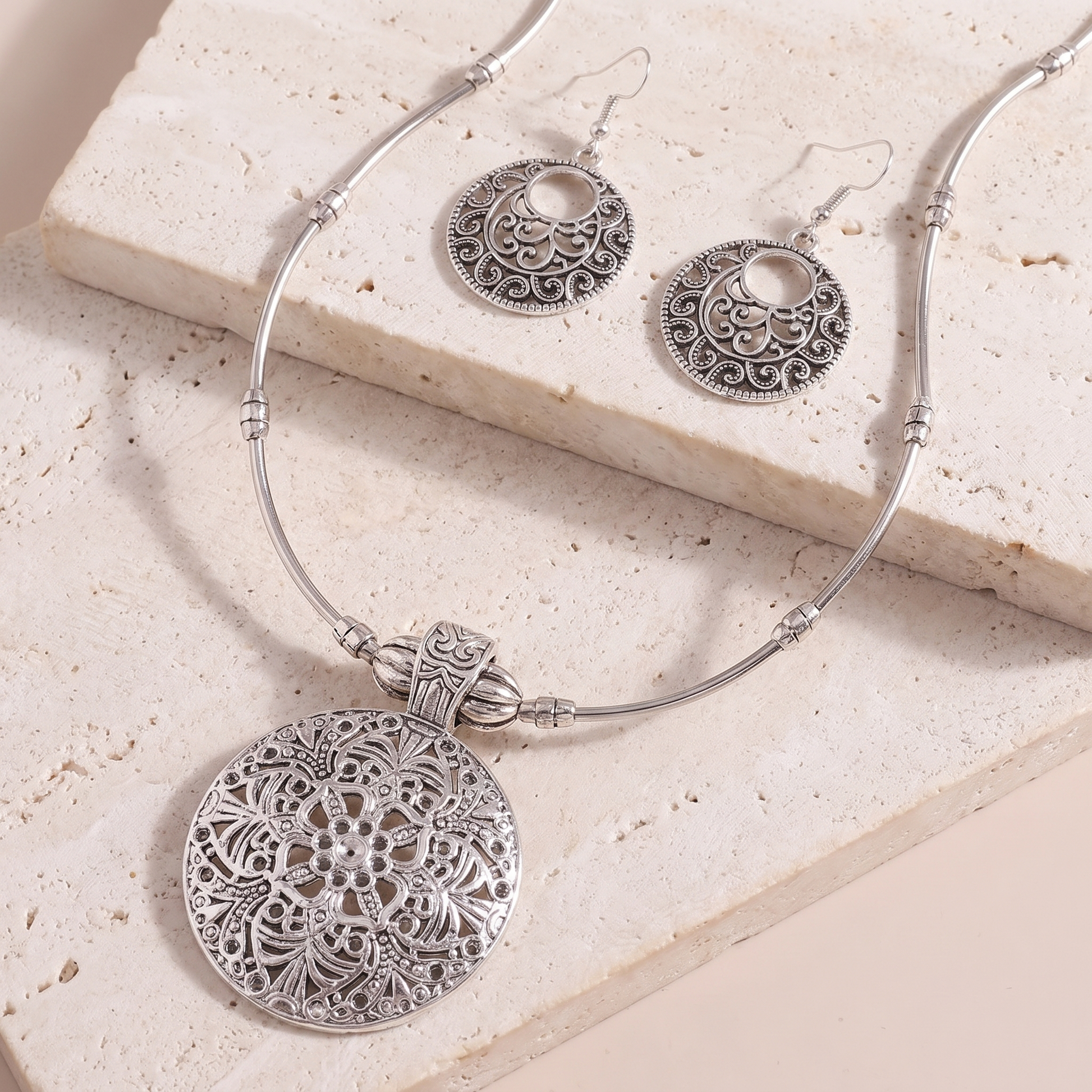 Lucca medallion pendant and earrings on a stone ledge