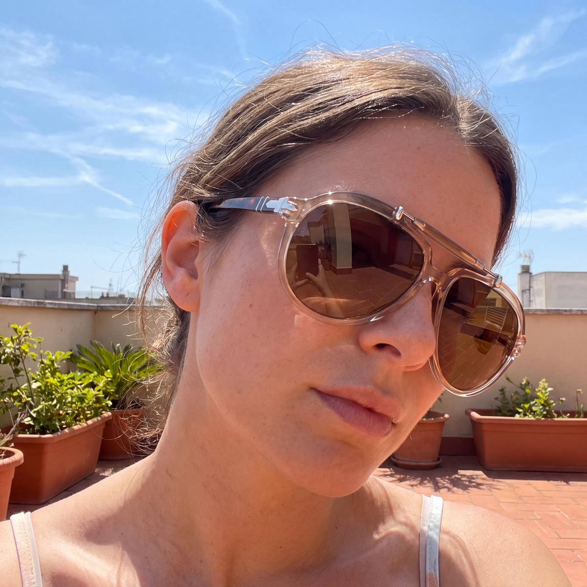 Woman wearing the Monterey Pilot Sunglasses in Clear Tan on a sunny rooftop terrace