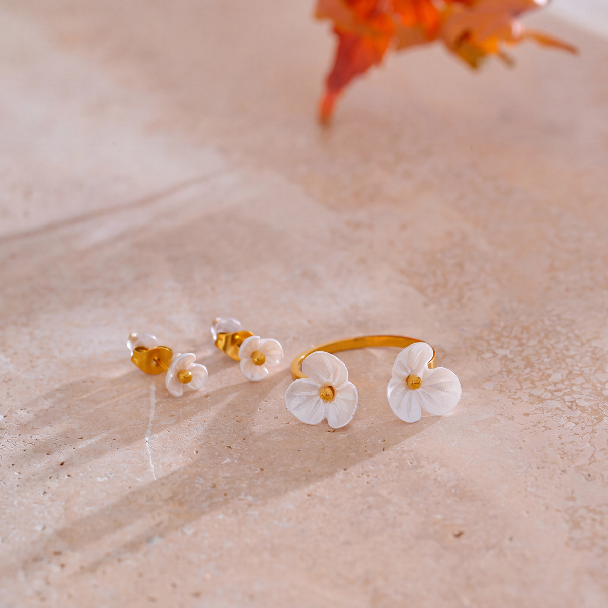 Rhea Blossom white resin flower ring and stud earrings on stone