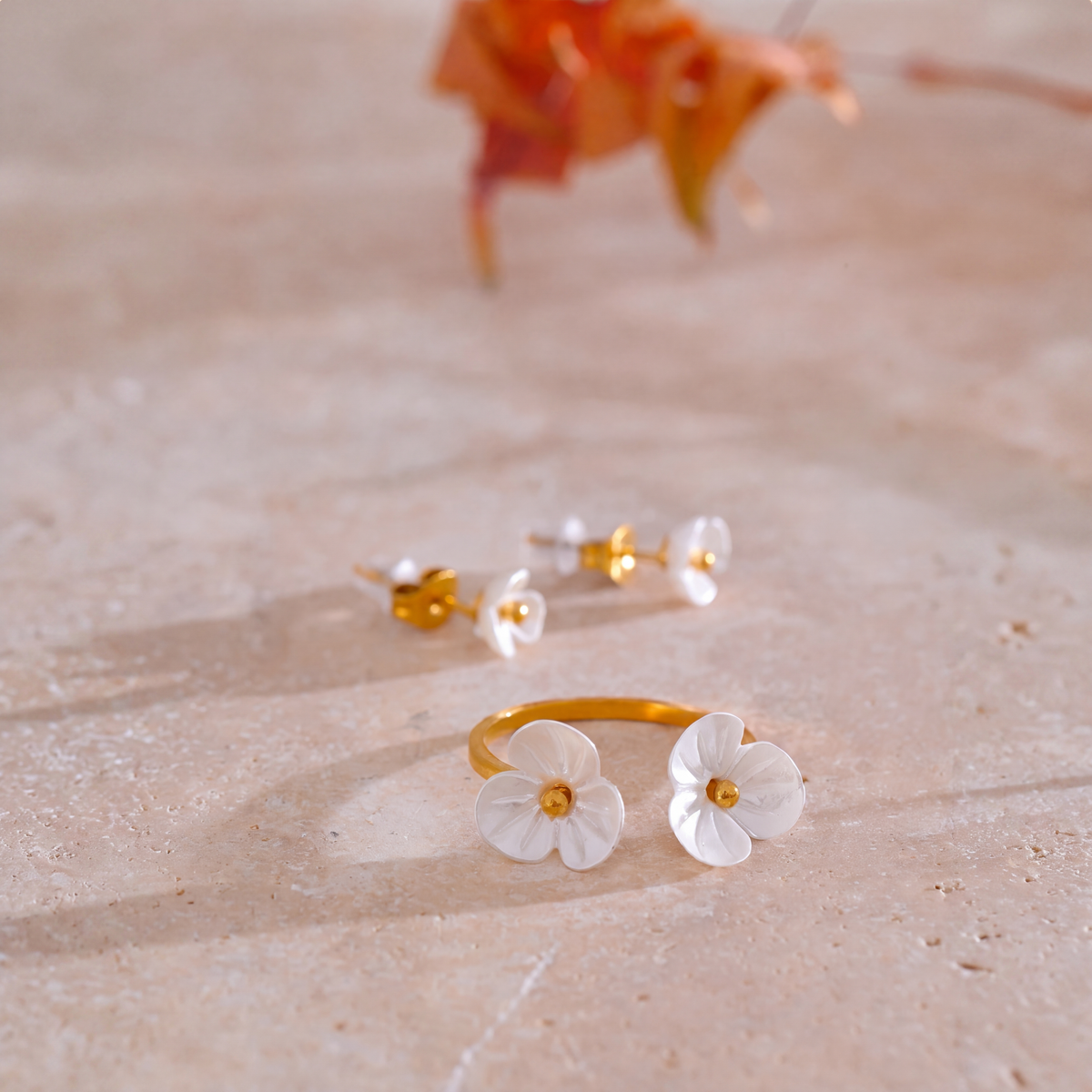 Rhea Blossom flower ring and earrings styled on travertine