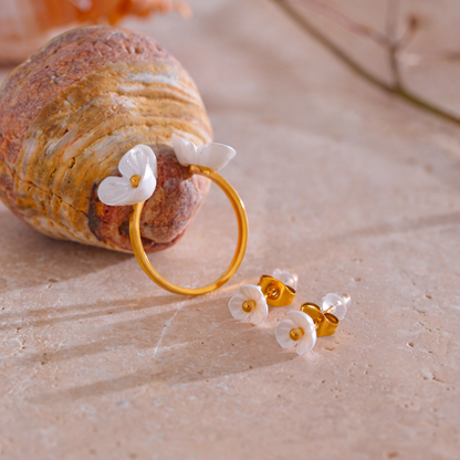 Rhea Blossom gold ring with white resin flowers beside stud earrings